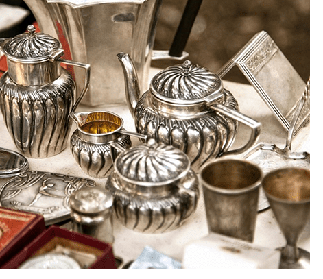 A table with silver tea pots and cups